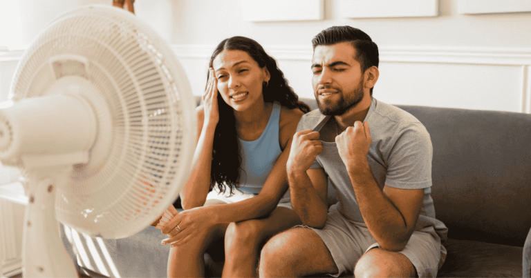 man and woman sitting in front of a fan to cool off